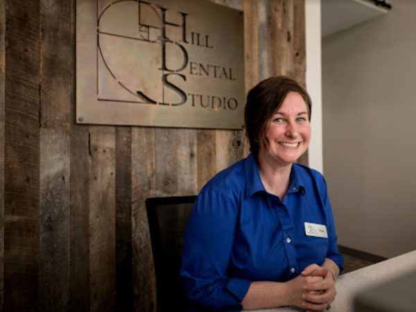 woman in blue shirt sitting at front desk of Hill Dental Studio